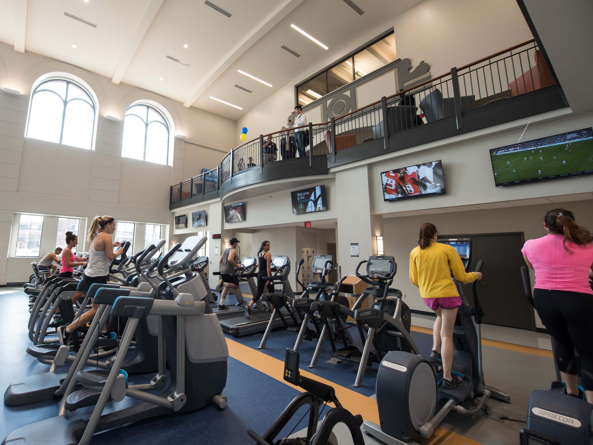 Cardio area with treadmills and elliptical machines, people exercising.