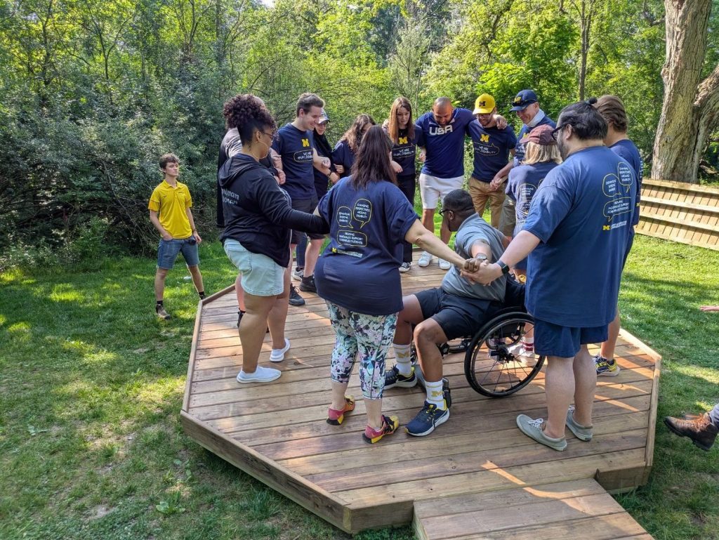Group activity on wooden platform outdoors with a wheelchair user.