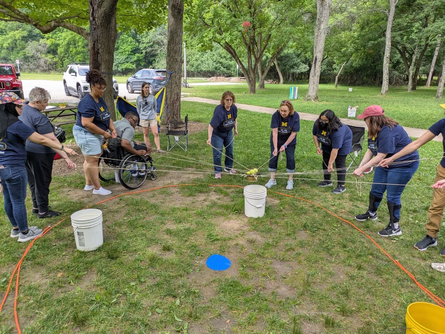 Participants play outdoor game with buckets and ropes.